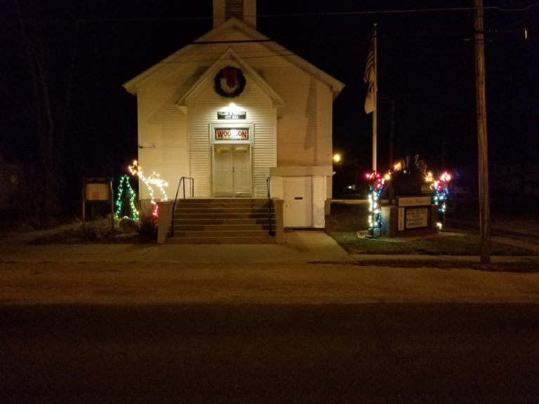 Village Hall at night decorated with holiday lights and a wreath