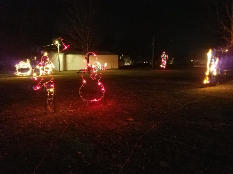 Lighted holiday figures, including a snowman, in the park at night