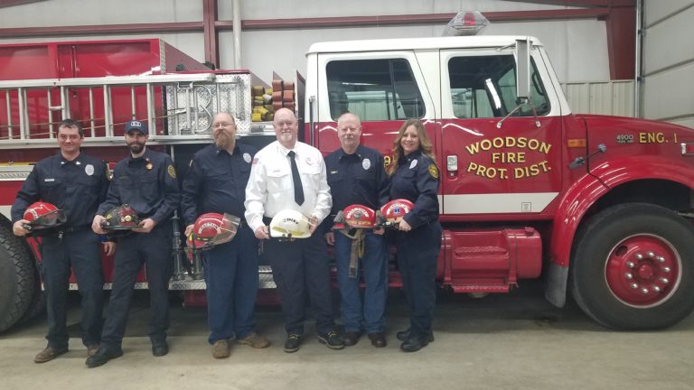 Woodson firefighters holding helmets in front of a fire engine