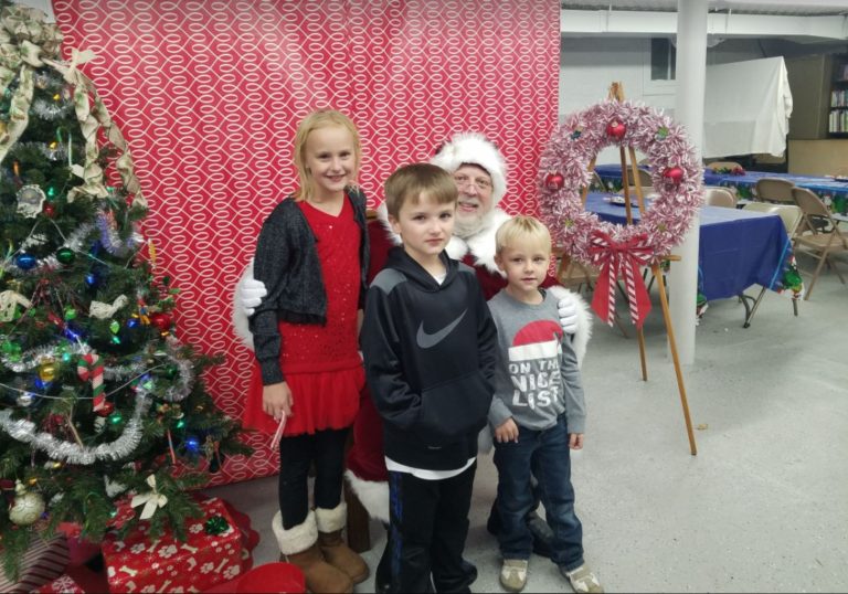 Santa Claus with three children beside a Christmas tree