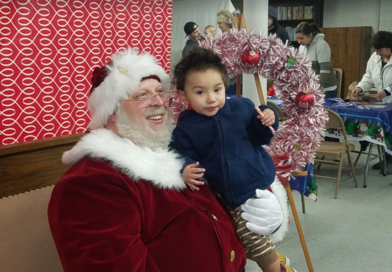 Santa Claus holding a toddler at the village holiday event