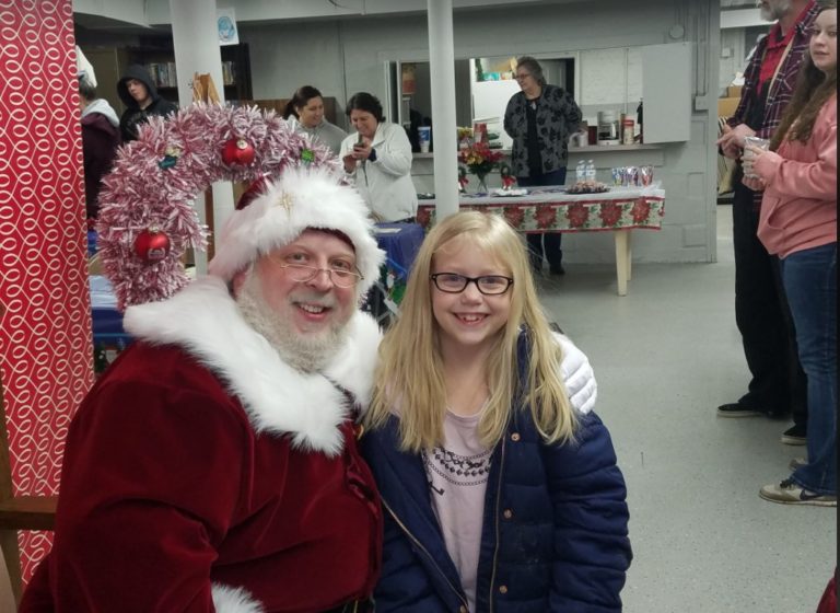 Santa Claus with a girl at the village holiday event