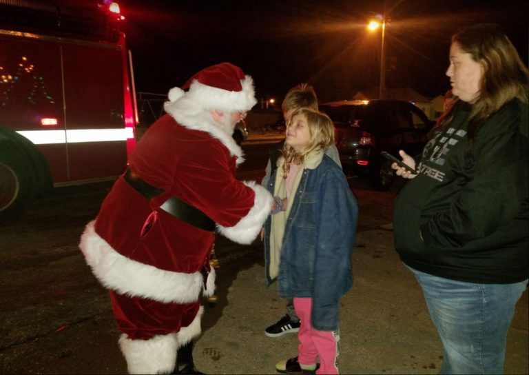Santa Claus greeting a child outdoors at night
