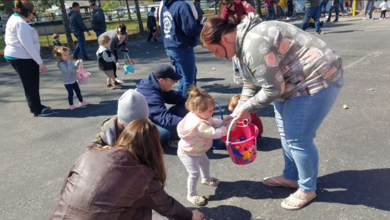 Parents helping toddlers collect eggs