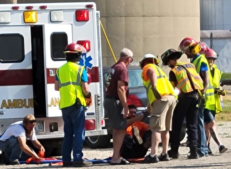 Firefighters and EMTs at a vehicle rescue drill beside an ambulance