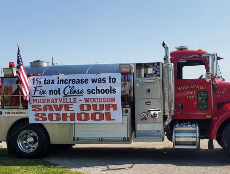 Fire engine carrying a Save Our School sign in the Fourth of July parade