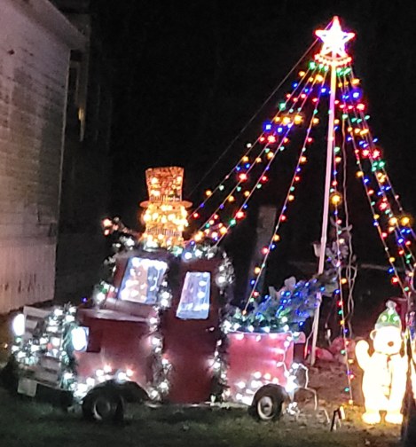 Holiday display with a lighted vintage pickup truck, a tree of lights and a snowman