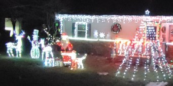 Home decorated with holiday lights and lit lawn figures at night
