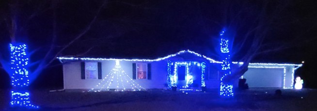 Home outlined in blue and white holiday lights at night