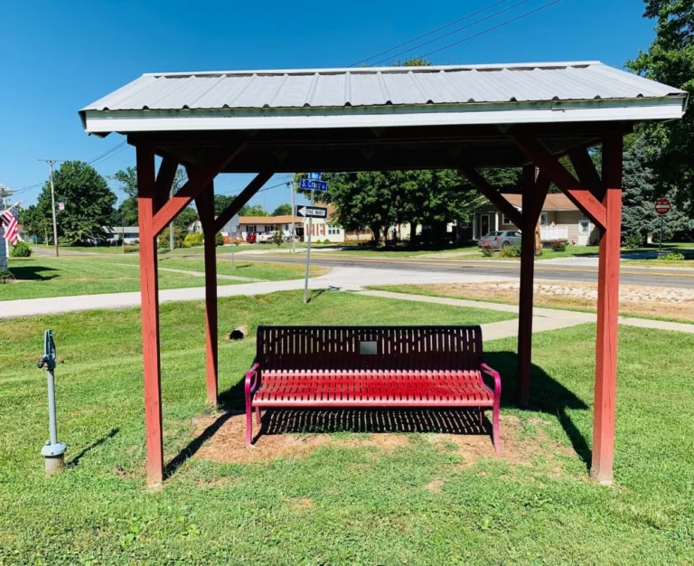 Covered bench under a small red-post shelter